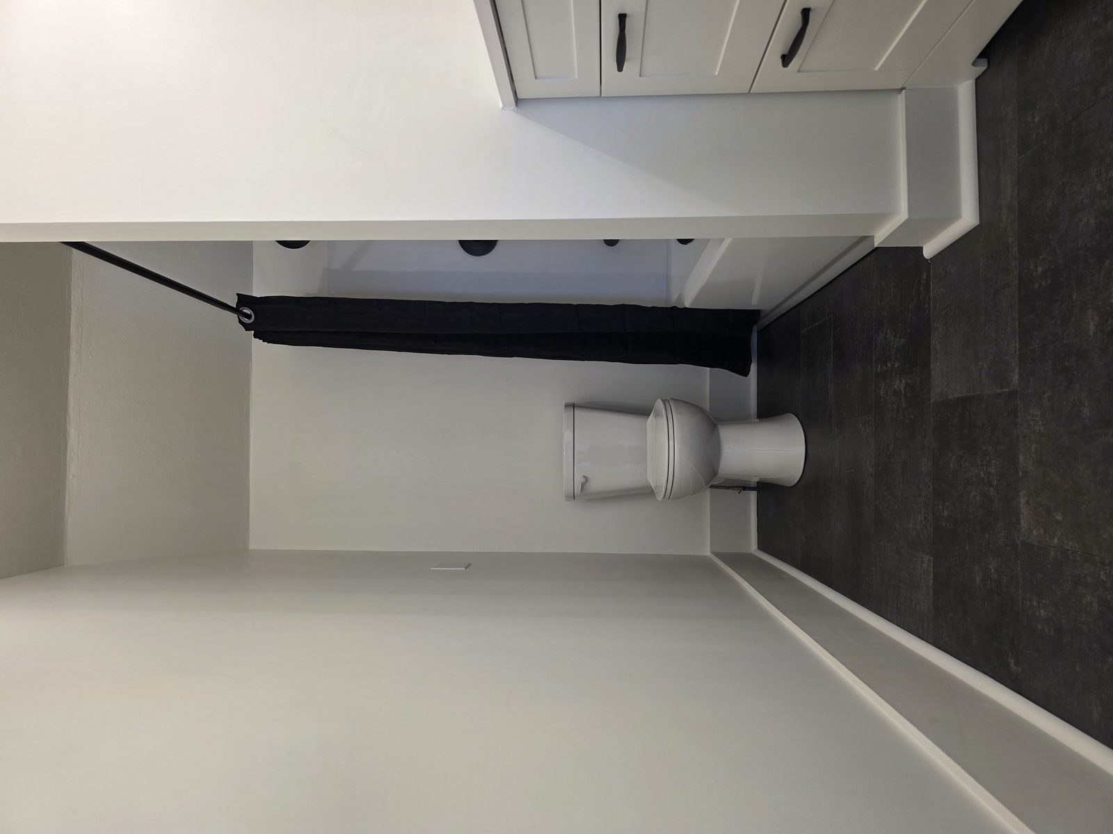 Modern bathroom remodel with dark tile and white vanity